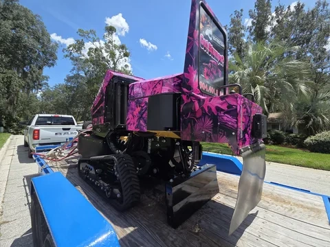 904Tree tracked stump grinder rear view — pink camo wrap with Got Stumps? sign on trailer